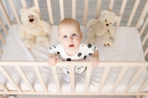 Why Your Baby Won’t Sleep in the Crib A baby is standing up in a crib