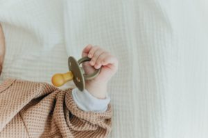 Can a Newborn Baby Sleep With a Pacifier? A newborn holding a pacifier