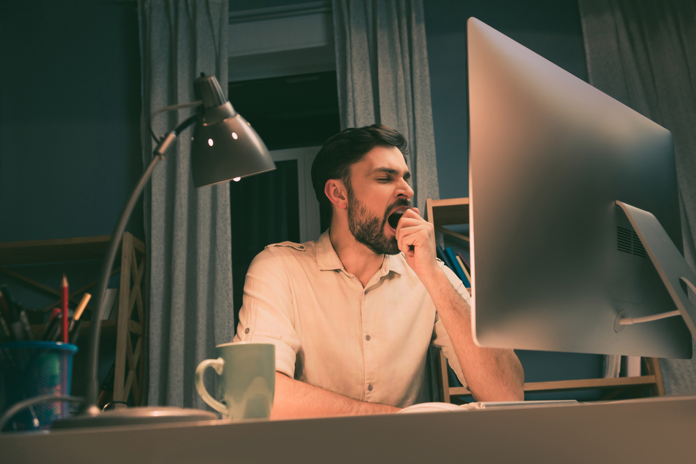 Tired man yawning at his desk